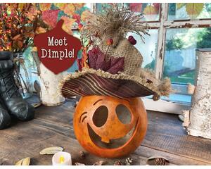 This is a fall gourd carved to look like a pumpkin. It has a handmade burlap hat decorated with fall leaves and berries. 